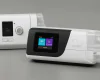 Side-by-side image of ResMed AirSense 11 and AirSense 10 CPAP machines, showing modern and older designs for a power efficiency comparison.
