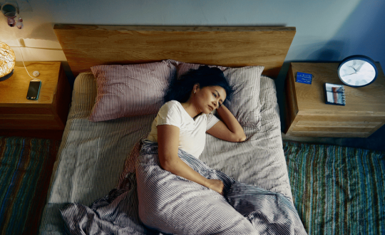 Indian adult sleeping on their side with head elevated in a calm, clutter-free bedroom