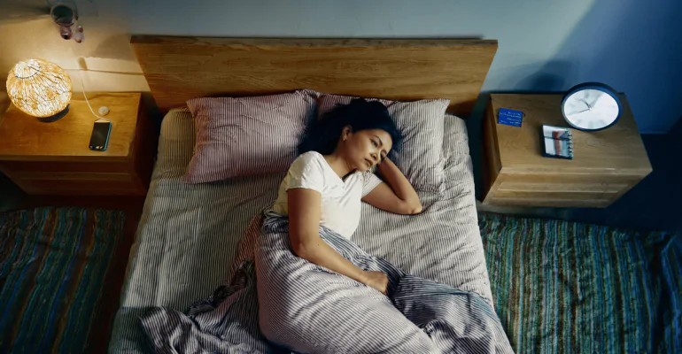 Indian adult sleeping on their side with head elevated in a calm, clutter-free bedroom
