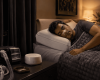 Person sleeping peacefully in a bedroom with CPAP machine, weighted blanket, nasal strip, blackout curtains, and white noise machine.